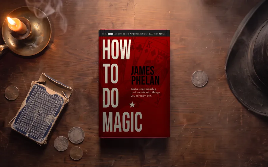 How to do Magic hardback on an old wooden table with a lit candle, a worn old card box, scattered old coins and a battered top hat in the spotlight