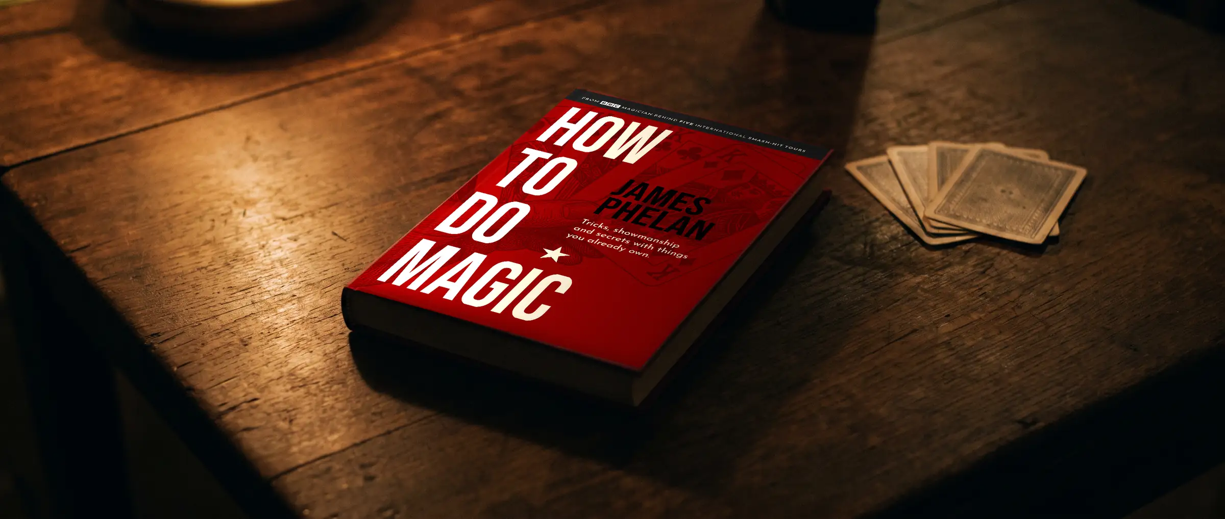 How to do Magic hardback on a dark wooden table with playing cards beside it